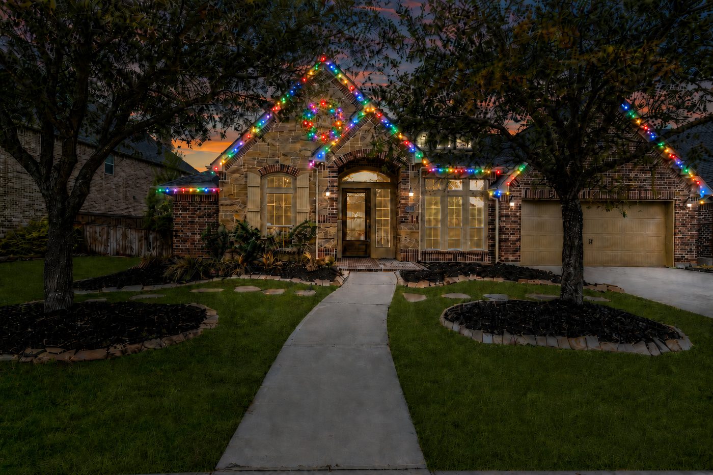 Large stone home with multicolor Christmas roofline lighting