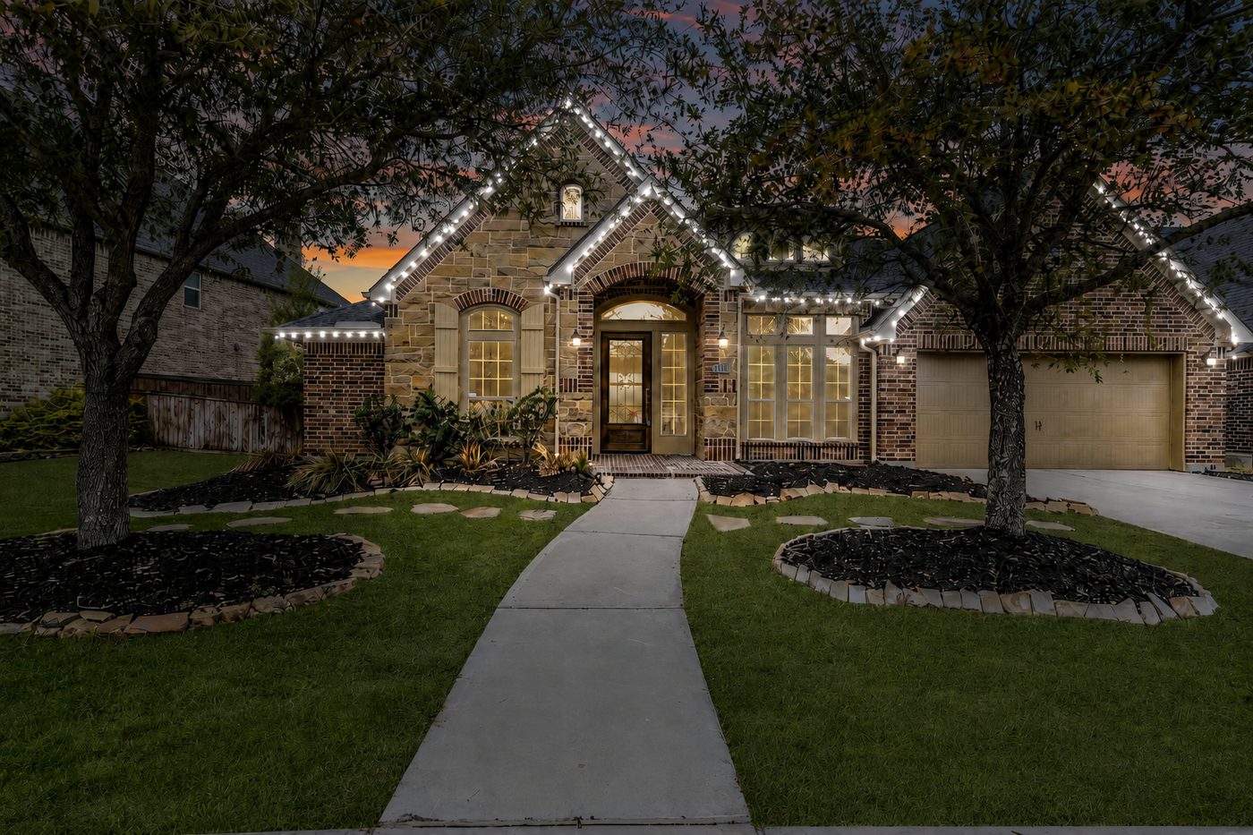 Large stone home with pure white Christmas roofline lighting