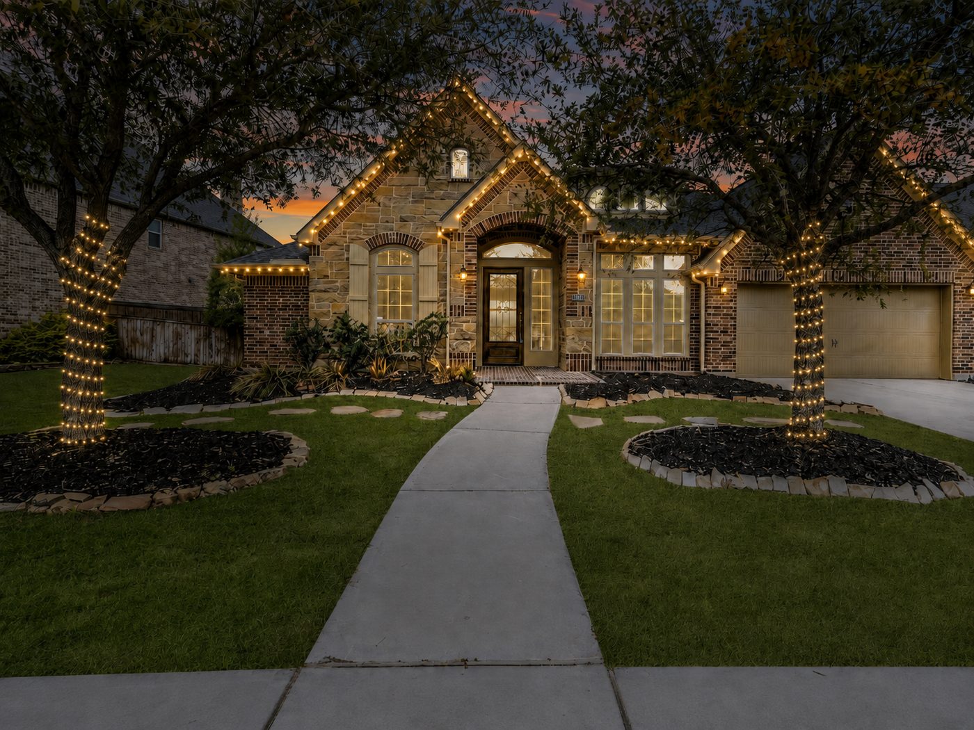 Boerne, Texas home with warm white roofline Christmas lights and wrapped oak trees