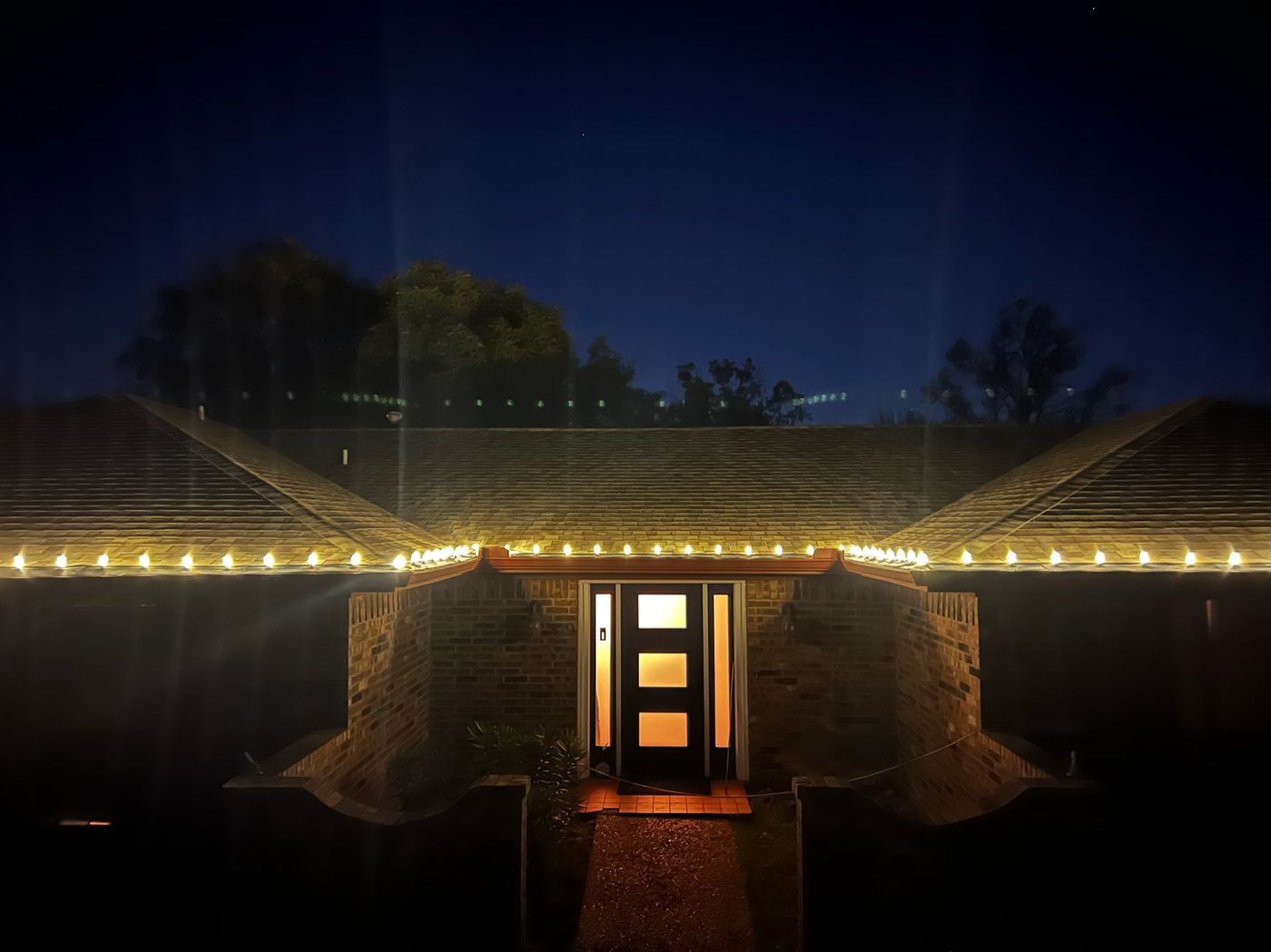Warm white C9 Christmas lights on a Hill Country home roofline at night